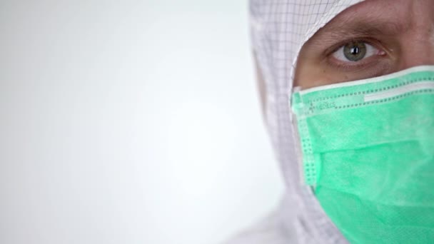 白い背景に隔離された保護スーツと外科用マスクを身に着けている自信のある男性の白人医師のクローズアップ肖像画 医学と医療の概念 生物学的危険 コロナウイルス Dan — ストック動画