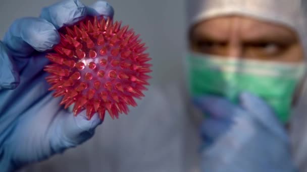 Koruyucu Kıyafetli Bir Erkek Bilim Adamı Elinde Kırmızı Bir Coronavirus — Stok video