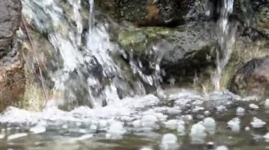 Yosunlu kayaların üzerinden akan nehrin yavaş hareketi. Ormandaki dağ nehri. Nehirler kayaların üzerinden akar. Akıntılı derenin güzel doğa sahnesi - Dan