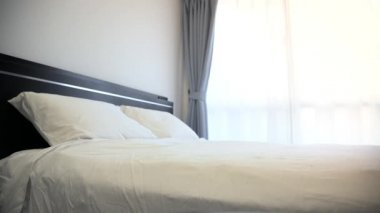 4K, otel odasında beyaz çarşaflı çift kişilik bir yatak.