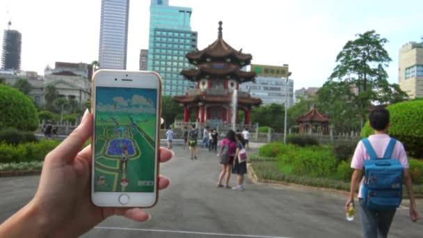 2016年8月6日 4K游戏平台在亚洲公园的应用程序上运行 在中国宝塔 丹纪念碑前 亚洲女子手持智能手机 在屏幕上显示出增强型现实手机游戏的地图Gps — 图库视频影像