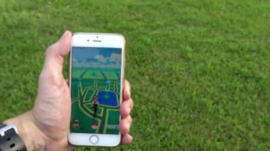 Taipei, Tayvan-06 Ağustos 2016: 4K Pokemon Go uygulaması parkta, Adam akıllı bir telefon tutuyor ve bahçede artırılmış gerçeklik mobil oyunu oynuyor. Yaratıkları bulmaya çalışıyorum - Dan