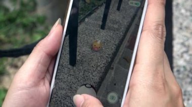 Taipei, Tayvan-06 Ağustos 2016: 4K Asya caddesinde Pokemon Go Uygulaması. Asyalı kadın ekranda gelişmiş gerçeklik mobil oyununu gösteren akıllı bir telefon tutuyor. Bir Weedle yaratığı yakalıyorum.