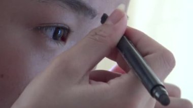 4K, genç Asyalı kadın kaşlarını boyuyor, kadın makyajını kapatıyor.