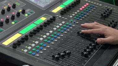 4k An ses mühendisi bir konserde canlı müzik yaparken mikseri ayarlar. Konsolu karıştırmak, farklı ses sinyallerini veya ses düzeyini birleştirmek için kullanılan elektronik bir aygıttır.