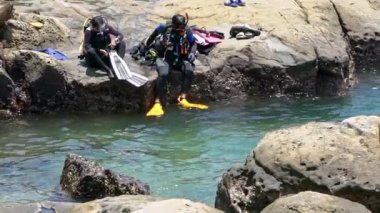 Keelung, Tayvan-16 Temmuz 2019: Bir kaya parçasından suya atlayan dalgıç. İnsanlar tropik bir adanın yaz tatilinde mavi okyanusta dalgıç ekipmanlarıyla yüzüyorlar.