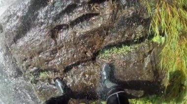 4K, şahsın şelaleden kaya tırmanışı yaparken ki görüntüsü. Adam ormanın derinliklerinde ipe tırmanıyor. Şelaleden halatla geçebilir miyiz? Koruyucu başlıklı maceraperest rappel-Dan