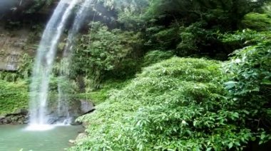 Keelung, Tayvan-25 Kasım, 2018: 4K, Şelaleden kaya tırmanışı pratiği. Adam ormanın derinliklerinde ipe tırmanıyor. Şelaleden halatla geçebilir miyiz? Koruyucu miğferi olan maceraperest tırmanışçı Dan