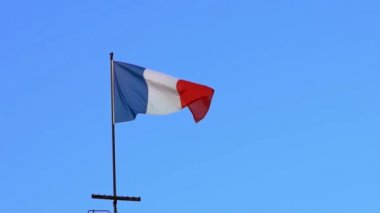 Fransa 'da bayrak direğinde rüzgarda dalgalanan Fransız bayrağının yavaş hareketi. Fransız bayrağının yavaş çekimde mavi gökyüzünün önünde sallanışı. Gerçek bir kumaş dokusunu kapat Asteğmen çırpınan Dan