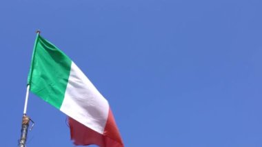 İtalya 'nın bir şehrinde bayrak direğinde rüzgarda sallanan İtalyan bayrağının yavaş hareketi. İtalyan sancağının yavaş çekimde mavi gökyüzünün önünde sallanışı. Gerçek bir kumaş dokusunu kapat Asteğmen çırpınan Dan