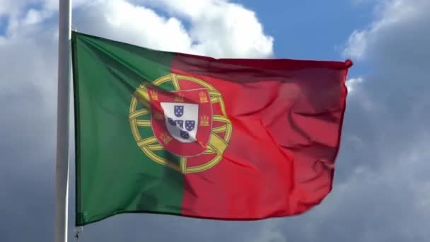 A portugál zászló lassú mozgása lengett a szélben egy város zászlórúdján. A portugál zászlók lassított mozgása lebeg nappal a kék ég előtt. Közelről egy igazi szövet textúra zászlós csapkodó - Dan