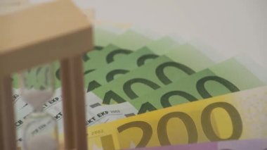 4K Dolly farklı değerlerde euro banknotlarıyla kum saatinin kaygan görüntüsü. Avro nakit para geçmişi. Banknotların üzerinde duran cam saat. Kriz konsepti zamanı.