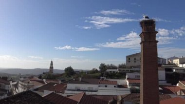 4K Stork, İspanya 'nın güneybatısındaki Badajoz eyaletinde yer alan Jerez de los Caballeros kasabasında mavi gökyüzü olan bir sütun üzerinde yuvada. - Dan.