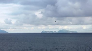 Akdeniz 'de uçan martıların Yavaş Hareketi, arka planda İtalya' nın Capri adası olan Napoli 'ye bakın. Okyanusun üzerinde uçan bir martı. Deniz kıyısındaki martı sürüsü. Kuşsuz uçuş Dan