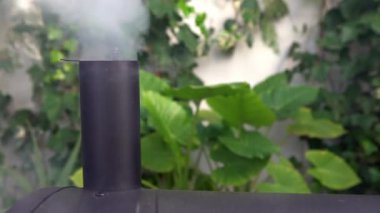 Seville, İspanya-26 Aralık 2018: 4K baca barbeküsü beyaz duman yayıyor. Evin bahçesinde ızgara ızgara ızgara ile yemek pişirmek. Siyah barbekü içicisi. Duman kapalı ızgaradan çıkıyor.