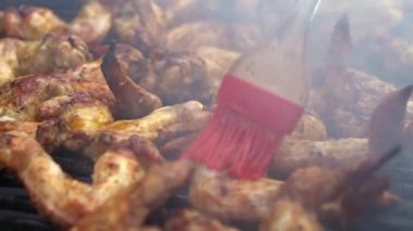 Barbekü ızgarasında marine edilmiş tavuk parçalarını sosla kaplayan adam. Şef ızgarada tavuk kanadı pişiriyor. Sıcak ve baharatlı ızgara tavuk pişirmek. Izgara ızgara Dan ile pişirilen yemekler.