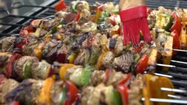 Şef sosla kaplanmış mangalda leziz şişler. Izgara et üzerinde brochette pişirmek. Izgara ızgarayla pişirilen yemekler. Dan evinin arka bahçesinde yemek pişiren adam.
