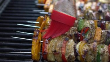 Yavaş Aşçı, sosla kaplanmış mangalda leziz şişler. Izgara et üzerinde brochette pişirmek. Izgara ızgarayla pişirilen yemekler. Dan evinin arka bahçesinde yemek pişiren adam.