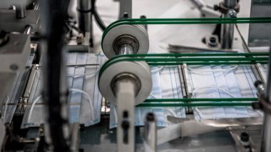Coronavirus için cerrahi maske üretimi. Fabrika atölyesinde koruyucu yüz maskesi. Covid19 virüsüne karşı korunmak için tek kullanımlık tıbbi giysi üretimi.