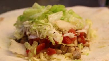 Profesyonel bir aşçı Meksika yemeklerini restoranda, tacolarda ve quesadillalarda pişiriyor. Darı tortillaları farklı malzemeler, peynir, domates, marul, tavuk ve sos için hazırlıyor.