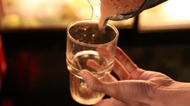 Adam domates suyunu bir restoranda bardağa dolduruyor.