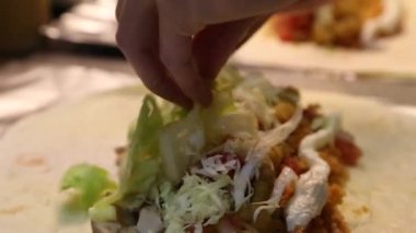 Asyalı bir adam Meksika yemeği hazırlıyor, Meksika restoranının mutfağında lezzetli dürümler yapıyor.