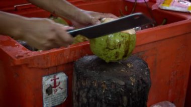 Siem Reap, Kamboçya-16 Nisan 2018: Satıcının Yavaş Hareketi yeşil bir hindistan cevizi kesiyor. Market caddesinde Kamboçya içkisi. İnsanlar hindistan cevizi keser. Asya 'da içecekler. Kamboçya 'daki Asya tezgahı