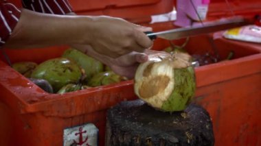 Tedarikçinin Yavaş Hareketi büyük yeşil bir hindistan cevizi kesiyor. Market caddesinde geleneksel Kamboçya içkisi. İnsanlar hindistan cevizi keser. Asya 'da egzotik içkiler. Kamboçya 'daki Asya tezgahı
