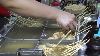 Kore sokak yemekleri çeşit çeşit oden malzemeler, insanlar balık köftesi ve diğer aperatifleri yiyor.