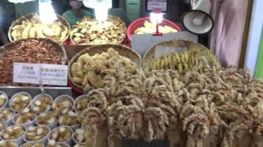 Taipei, Tayvan 24 Mayıs 2015: 4k Mutlu Asyalı kadın Tamsui Caddesi 'ndeki gece pazarından kızarmış kalamar ve diğer geleneksel balık yemi alır. Tayvan, Taipei 'de çekilmiş. - Dan.