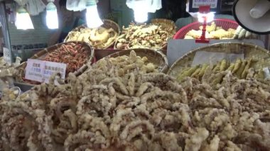 Taipei, Tayvan 24 Mayıs 2015: Tamsui 'deki gece pazarında müşterilere kızarmış mürekkep balığı ve diğer geleneksel balık yemekleri servis eden 4K Asyalı. Tayvan, Taipei 'de çekilmiş. - Dan.