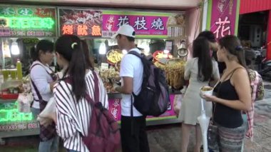 Taipei, Tayvan 24 Mayıs 2015: 4k Mutlu Asyalı kadın Tamsui Caddesi 'ndeki gece pazarından kızarmış kalamar ve diğer geleneksel balık yemi alır. Tayvan, Taipei 'de çekilmiş. - Dan.