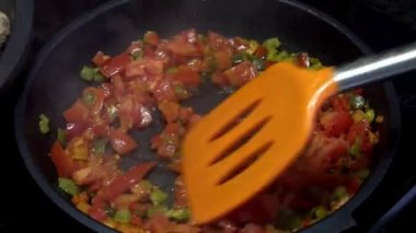 4K, Şef kızarmış tavada domatesli kırmızı ve yeşil biber pişiriyor. Lezzetli ve sağlıklı sebzeli güveç. Farklı renkte organik biber dilimleri. Lezzetli, besleyici organik beslenme