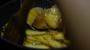 Yüksek sıcaklıktaki tavada yağda birkaç kabarcık görünene kadar ağır ateşte kızartılan yiyecekler. Patates kızartması. Patates, kaynar yağın içine atılmış. Lokantada lezzetli fast food kavramı