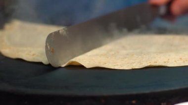 Paris caddesinde metal bir ızgarada krep pişiren yavaş çekim satıcısı. Çikolatalı tatlı ile yakın plan krep. Lezzetli fast food. Bir el dışarıda krep yapıyor. Şef leziz bir krep-Dan pişirir.