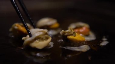 4K Mutfak Deniz Yemekleri. Şef ızgarada istiridye pişiriyor. Mutfak restoranında pişirmek için çubuk kullanmaya yakın çekim. - Dan.