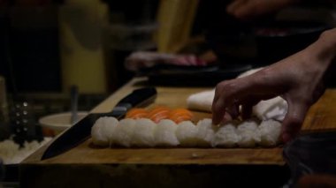 Yavaş Asyalı şef, Japonya 'nın mutfağında suşi yapmak için çiğ balık dilimini hazırla. Japon restoranında yemek yapan bir adam. Satılık leziz Asya yemekleri yapan ellerinizi kapayın.