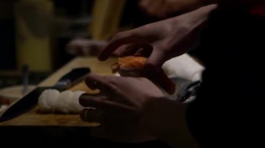 Yavaş Asyalı şef, Japonya 'nın mutfağında suşi yapmak için çiğ balık dilimini hazırla. Japon restoranında yemek yapan bir adam. Satılık leziz Asya yemekleri yapan ellerinizi kapayın.