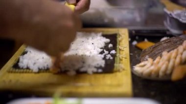 4K, Makizushi hazırlanıyor. Ev yapımı suşi yapıp evdeki ahşap masada yuvarlanacağız. Aşçı adam geleneksel Japon yemeklerini evde ya da restoranda mutfak masasında hazırlıyor.