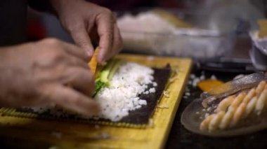 4K, Makizushi hazırlanıyor. Ev yapımı suşi ve ekmek yapma süreci. Erkek aşçının elleri evde ya da mutfak masasında geleneksel Japon yemeklerini hazırlıyor.