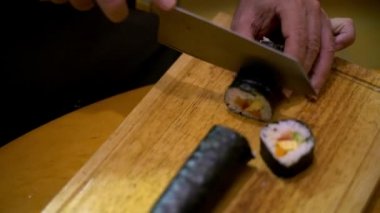 4K, Makizushi hazırlanıyor. Ev yapımı suşi ve ekmek yapma süreci. Erkek aşçının eli bıçakla kesilir. Geleneksel bir Japon yemeği evde ya da restoranda.