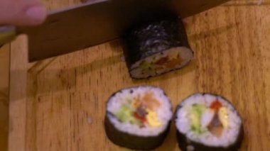 Makizushi 'nin Yavaş Hareketi hazırlanıyor. Mutfaktaki restoranda geleneksel Japon yemeklerini bıçakla kesen aşçı elleri. Ev yapımı suşi yap ve Dan 'deki ahşap masada yuvarlan.