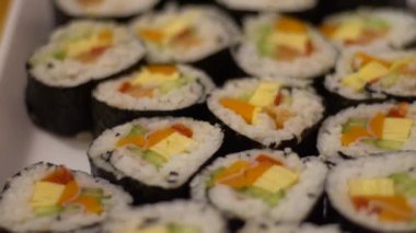 Beyaz tabakta servis edilen somonlu lezzetli Makizushi seti. Restoranda geleneksel suşi sarılmış Japon yemeği. Pirinç haşhaş ve gurme menüde balık ve pilav.