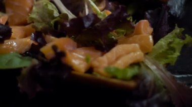 Somon kesesi hazırlanırken yavaş hareket ediyor. Kadın şefin elleri mutfaktaki restoranda geleneksel Japon yemeklerini hazırlıyor. Ev yapımı Dan 'de ahşap masada ev yapımı suşi yapmak.