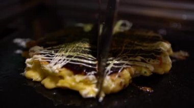 4K Okonomiyaki Japon yemeği. Soya soslu ve mayonezli. Krepi un ve suyla pişir, doğranmış lahana, yumurta, soğan ve deniz ürünleri. Monjayaki 'yi Pişirmek Bir Japon Restoranında Kızartıldı