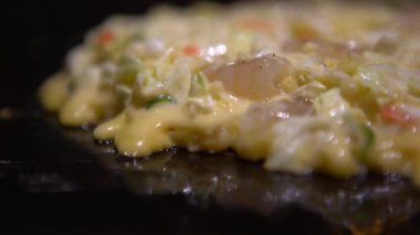 4K Okonomiyaki Japon yemeği. Çeşitli malzemeler içeren krep, hamurlu, un ve sudan yapılmış, doğranmış lahana, yumurta, soğan ve deniz ürünleri. Monjayaki 'yi Japon restoranında kızartıyorlar. Dan.