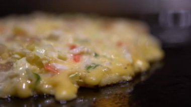 4K Okonomiyaki Japon yemeği. Çeşitli malzemeler içeren krep, hamurlu, un ve sudan yapılmış, doğranmış lahana, yumurta, soğan ve deniz ürünleri. Monjayaki 'yi Japon restoranında kızartıyorlar. Dan.
