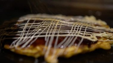 4K Okonomiyaki Japon yemeği. Soya soslu ve mayonezli. Krepi un ve suyla pişir, doğranmış lahana, yumurta, soğan ve deniz ürünleri. Monjayaki 'yi Pişirmek Bir Japon Restoranında Kızartıldı