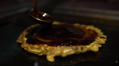 4K Soya sosunu Okonomiyaki Japon yemeğine koy. Krepi un ve suyla pişir, doğranmış lahana, yumurta, yeşil soğan ve deniz ürünleri. Monjayaki 'yi Pişirmek Bir Japon restoranında Kızartılmak - Dan