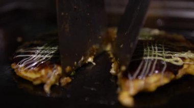 4K Okonomiyaki Japon yemeği. Soya soslu ve mayonezli. Krepi un ve suyla pişir, doğranmış lahana, yumurta, soğan ve deniz ürünleri. Monjayaki 'yi Pişirmek Bir Japon Restoranında Kızartıldı